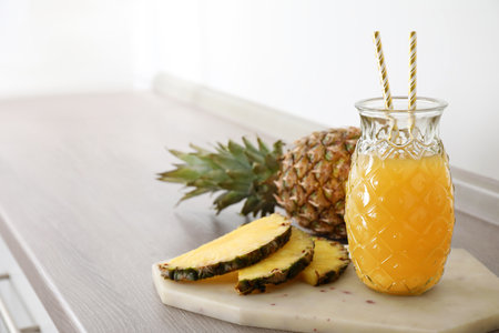 Delicious pineapple juice and fresh fruit on wooden table, space for textの写真素材