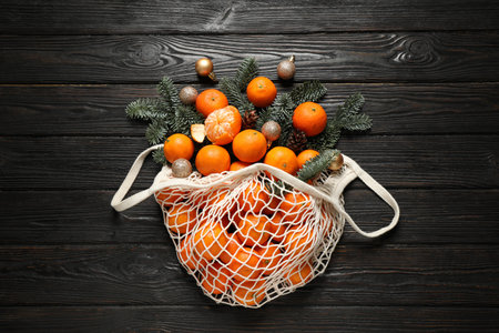 Flat lay Christmas composition with fresh tangerines in mesh bag on dark wooden tableの写真素材