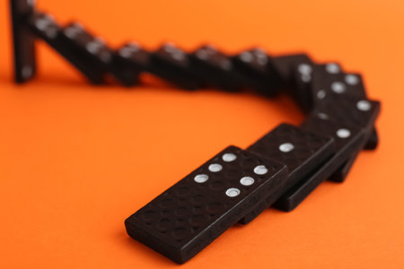 Brown domino tiles falling on orange background, closeupの写真素材