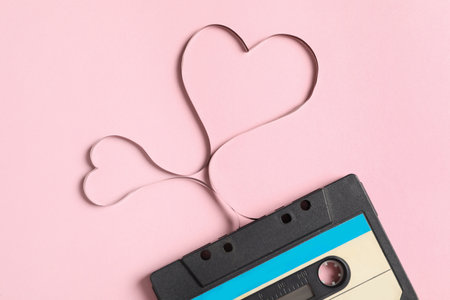 Music cassette and hearts made with tape on pink background, top view. Listening love songの写真素材