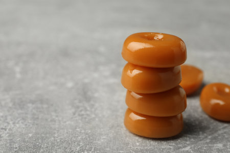 Stacked tasty hard toffee candies on light grey table, closeup. Space for textの写真素材