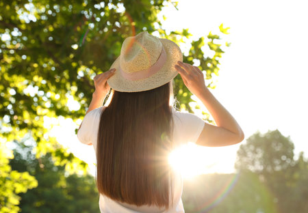 Young woman in hat outdoors on sunny day, back viewの写真素材
