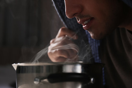 Man with plaid doing inhalation above saucepot, closeupの写真素材