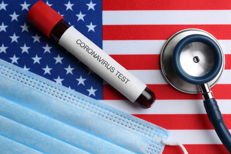 Test tube with blood sample, medical mask and stethoscope on American flag, flat lay. Coronavirus pandemic in USAの写真素材