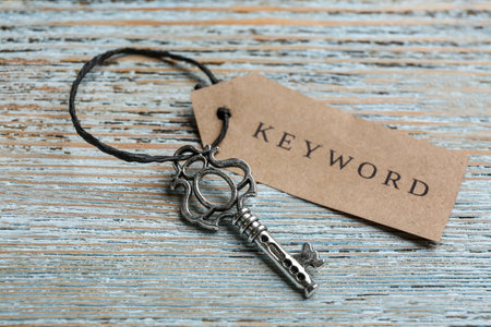 Key with tag KEYWORD on blue wooden background, closeup