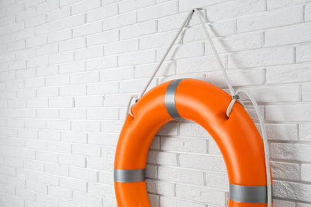 Orange lifebuoy and space for text on white brick wall. Rescue equipmentの写真素材