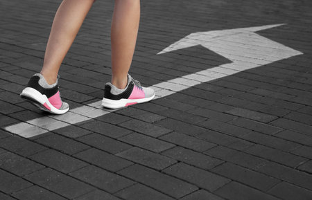 Woman going along road with arrow marking, closeupの写真素材
