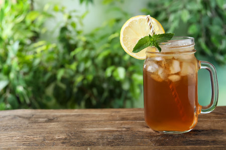 Delicious iced tea in mason jar on wooden table outdoors, space for textの写真素材