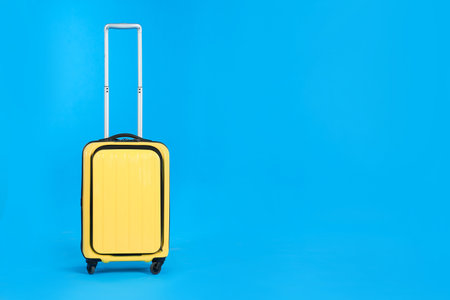 Yellow travel suitcase on light blue background, space for text. Summer vacationの写真素材