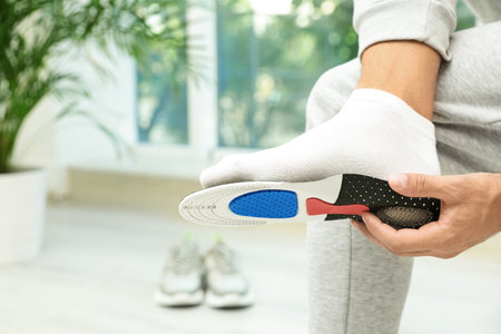 Man fitting orthopedic insole indoors, closeup. Foot careの写真素材