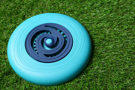 Light blue plastic flying disk on green grassの写真素材