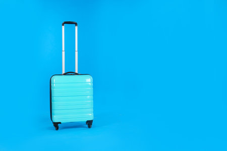 Travel suitcase on light blue background, space for text. Summer vacationの写真素材