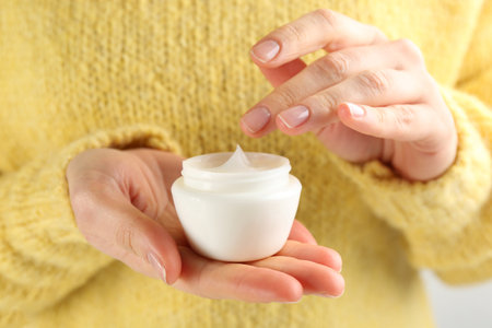 Woman holding jar of moisturizing cream, closeup. Cosmetic product for winterの写真素材