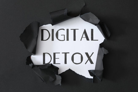 Words DIGITAL DETOX on white background, view through hole in black paperの写真素材