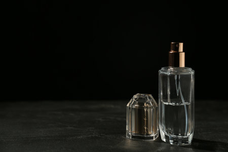 Bottle of perfume on dark table against black background, space for textの写真素材
