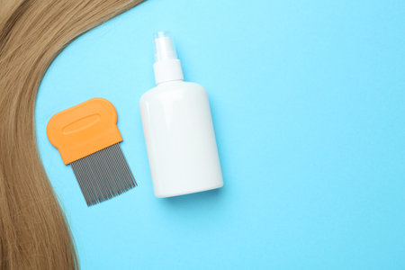 Comb and anti lice spray, blond hair on light blue background, flat lay. Space for textの写真素材