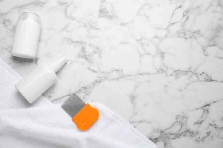 Products for anti lice treatment, metal comb and towel on marble background, flat lay. Space for textの写真素材