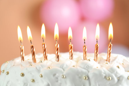 Birthday cake with burning candles on blurred background, closeup