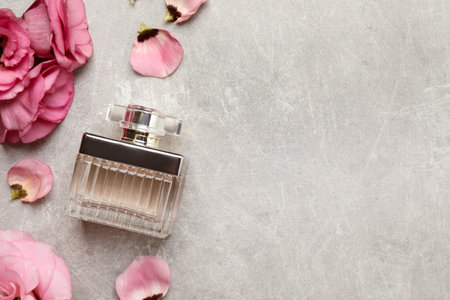 Flat lay composition with bottle of perfume and eustoma flowers on grey textured background, space for textの写真素材