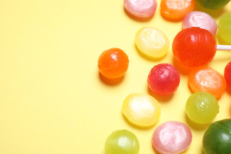 Many different hard candies on yellow background, closeup. Space for textの写真素材