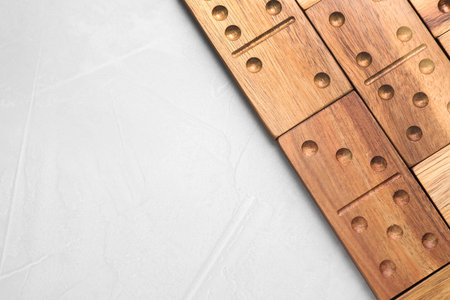 Wooden domino tiles on light grey table, flat lay. Space for text