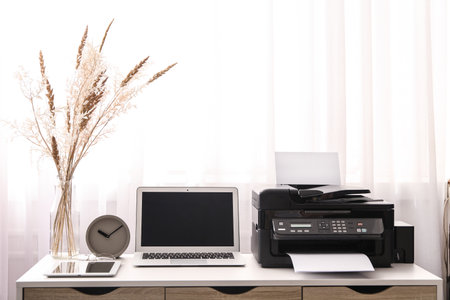 Modern printer, laptop and office supplies on white table indoorsの写真素材