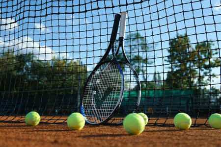 Tennis balls and rackets near net on clay courtの写真素材