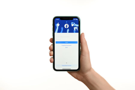 MYKOLAIV, UKRAINE - JULY 9, 2020: Woman holding iPhone X with Facebook app on white background, closeupのeditorial素材