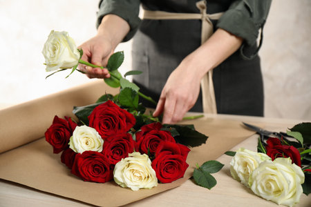 Woman making luxury bouquet of fresh roses at wooden table, closeupの写真素材