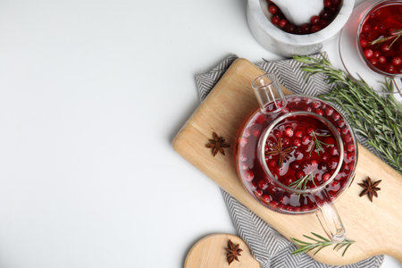 Tasty hot cranberry tea with rosemary and anise on white table, flat lay. Space for textの写真素材
