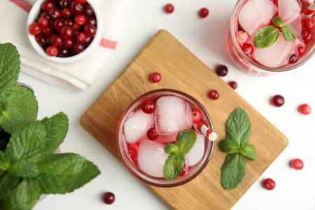 Tasty refreshing cranberry cocktail with mint on white table, flat layの写真素材