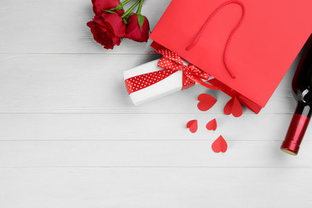 Flat lay composition with gift box and roses on white wooden background, space for text. Valentine's Day celebrationの写真素材