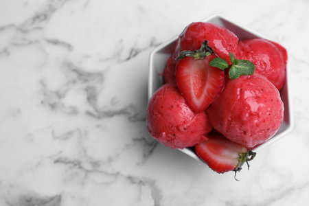 Yummy strawberry ice cream in bowl on white marble table, top view. Space for textの写真素材