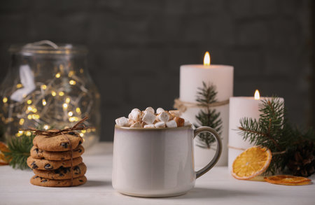 Cup of hot drink with marshmallows and cookies on white tableの写真素材