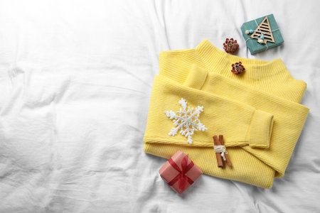 Yellow warm sweater and decorations on white bedsheet, flat lay. Space for textの写真素材