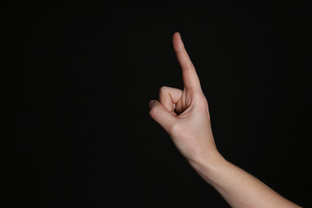 Woman pointing at something on black background, closeup. Finger gestureの写真素材