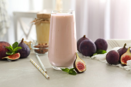 Delicious fig smoothie in glass on light tableの写真素材