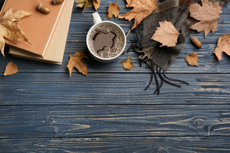 Flat lay composition with cup of hot drink and autumn leaves on blue wooden table, space for text....