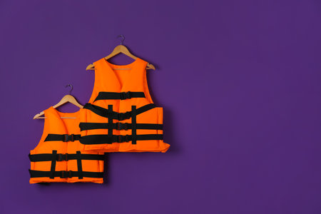 Orange life jackets on violet background. Space for text