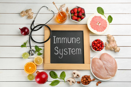 Chalkboard with phrase Immune System, stethoscope and fresh products on white wooden table, flat layの写真素材
