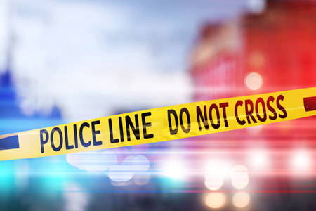 Yellow law enforcement tape isolating crime scene. Blurred view of the city, toned in red and blue police car lightsの写真素材