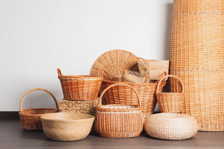 Many different wicker baskets made of natural material on floor near light wallの写真素材