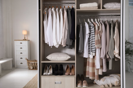 Wardrobe closet with different stylish clothes, shoes and home stuff in roomの写真素材