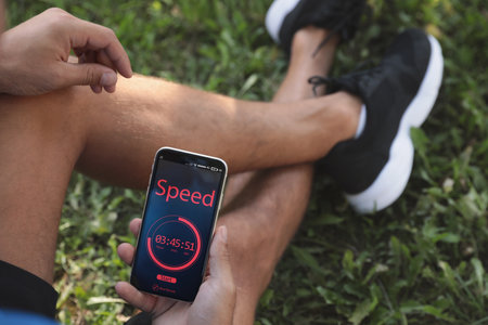 Man using fitness app on smartphone outdoors, closeupの写真素材