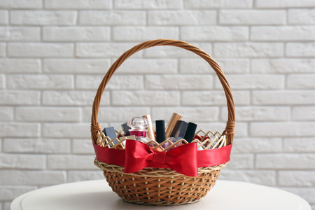 Wicker gift basket with cosmetic products on table near white brick wallの写真素材