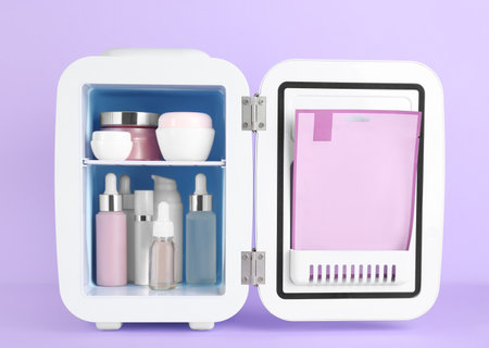 Open cosmetic refrigerator with skin care products on violet backgroundの写真素材