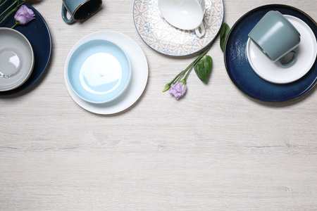 Flat lay composition with beautiful dishware and flowers on white wooden table. Space for textの写真素材