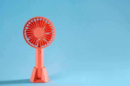 Modern electric fan on light blue background. Space for textの写真素材