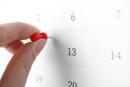 Woman pinning Friday 13th on calendar, closeup. bad luck superstitionの写真素材