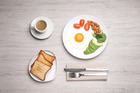 Tasty breakfast with fried egg, toasts and coffee served on white wooden table, flat layの写真素材